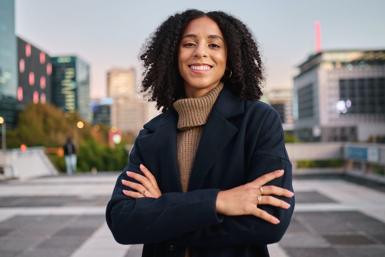 Black woman, portrait smile and arms crossed in the city for vision, ambition or career success. Co